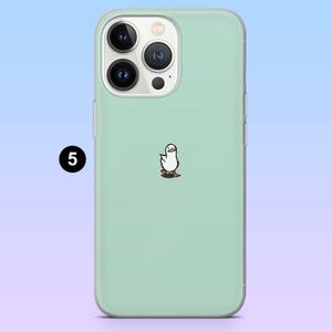 May include: A pale green phone case with a transparent edge. The case has a small cartoon duck illustration. The phone case has three camera lenses and a flash. The number 5 is in a black circle in the upper left corner.