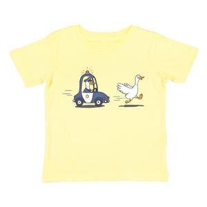 May include: A yellow short-sleeved t-shirt featuring a cartoon illustration of a goose running away from a police car driven by a goose.