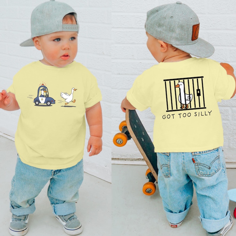 May include: A yellow short-sleeved t-shirt with a cartoon goose being chased by a police car on the front and a cartoon goose in a jail cell with the text "Got Too Silly" on the back. The shirt is being modelled by a child wearing blue jeans and a grey baseball cap.