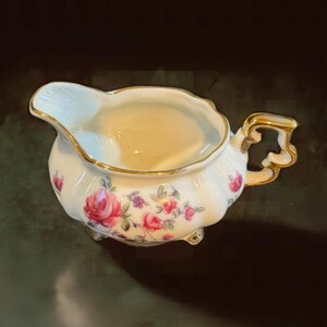 Vintage small floral painted porcelain pitcher with gold trim.