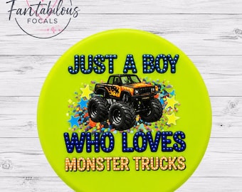 Puede incluir: Un círculo verde lima con el texto "JUST A BOY WHO LOVES MONSTER TRUCKS" en letras azules y doradas. Un gráfico de un camión monstruo naranja y negro está en el centro, rodeado de estrellas y confeti.