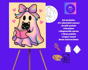 May include: A DIY paint kit featuring a pre-sketched canvas with a cartoon ghost and black cat reading a book. The ghost has a rainbow bow and is surrounded by pink hearts. The kit includes acrylic paints, brushes, an apron, a palette, a paper towel, and instructions.