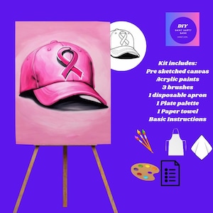 May include: A pink canvas on an easel depicts a baseball cap with a pink ribbon, a symbol of breast cancer awareness. The image is part of a DIY paint kit, including acrylic paints, brushes, an apron, and a palette.