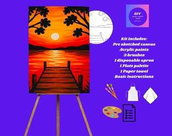 May include: A DIY paint party kit featuring a pre-sketched canvas of a sunset over water, acrylic paints, brushes, an apron, palette, paper towel, and instructions. The canvas is displayed on a wooden easel.