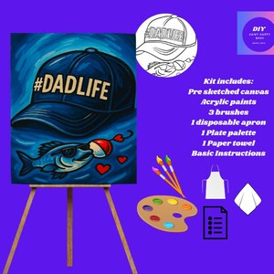 May include: A DIY paint kit featuring a pre-sketched canvas with a blue baseball cap design that says #DADLIFE, a fish wearing sunglasses, and hearts. The kit includes acrylic paints, brushes, an apron, a palette, and instructions.