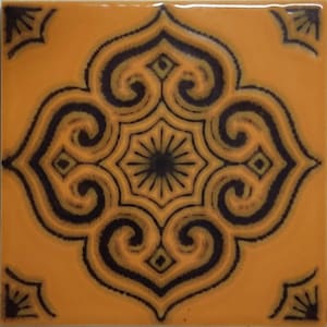 May include: Square ceramic tile with a repeating ornate design. The tile has a mustard yellow background with a dark navy blue and olive green floral pattern. The design includes swirling shapes, a central starburst, and corner accents.