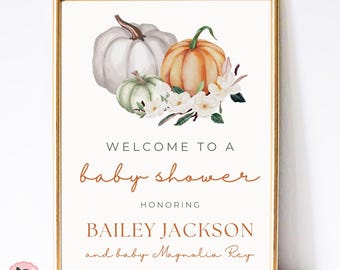 May include: A white and orange pumpkin baby shower sign with white flowers and green leaves. The sign says "Welcome to a baby shower honouring Bailey Jackson and baby Magnolia Rey".