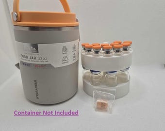 May include: A gray 32oz stainless steel insulated food jar with an orange handle and lid. Next to it is a white rack holding multiple small glass vials with orange caps. A small plastic bag contains a few small orange tablets.