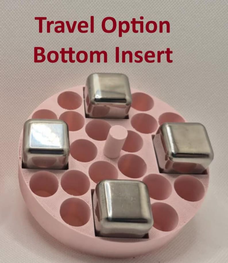 May include: A pink, circular travel option bottom insert with multiple round holes and four stainless steel cubes. A small, light pink cylinder is in the center. The text "Travel Option Bottom Insert" is in red.