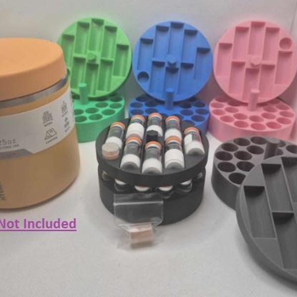 May include: An orange food jar with a lid and a tag, next to several colored circular holders. The holders are green, blue, pink, and gray. The holders have various holes and slots to hold small vials. The text "Container Not Included" is visible.