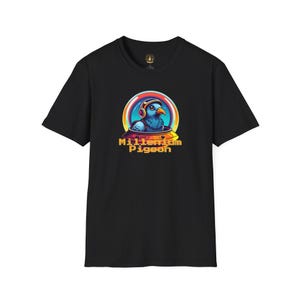 May include: Black t-shirt featuring a colorful graphic of a blue pigeon wearing headphones inside a retro-style spaceship. The text "Millennium Pigeon" is below the image in a yellow and orange font. The shirt is made of a soft material.