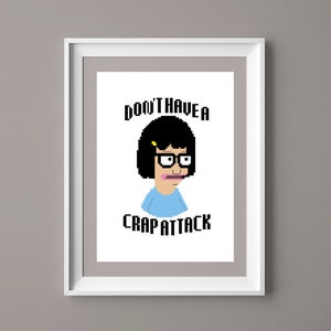 Puede incluir: Impresión enmarcada en blanco con un personaje de dibujos animados pixelado con gafas y una parte superior azul. El texto "DON'T HAVE A CRAP ATTACK" se muestra encima y debajo de la imagen del personaje. La impresión está en un marco blanco.