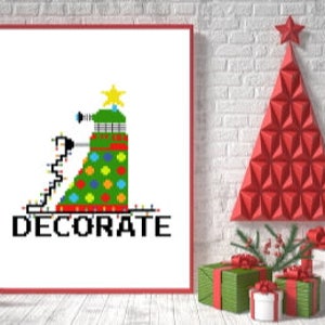 May include: A cross-stitch pattern featuring a green Christmas tree decorated with colorful ornaments and a star on top. The tree is topped with a black and white robot with a red eye. The text "DECORATE" is below the tree.