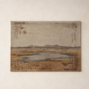 May include: Rectangular woven rug with a landscape design. The rug features a muted color palette of beige, brown, and blue, depicting a serene scene with mountains and a body of water. Decorative border elements frame the edges.