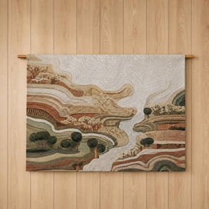 May include: A rectangular wall hanging featuring a textured, tufted landscape design. The artwork displays layered, undulating hills in shades of cream, beige, terracotta, and sage green, with small tufted tree clusters scattered throughout the scene.