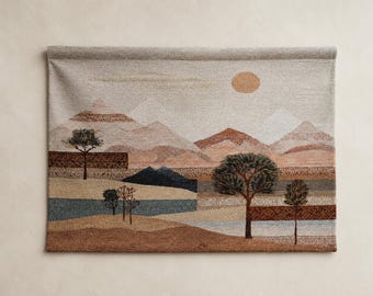May include: A rectangular woven wall hanging featuring a landscape scene with layered mountains in shades of beige, tan, and rust. A circular sun sits in the sky above trees and a blue river. The design includes geometric patterns and textured lines.