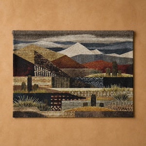 May include: A rectangular woven wall tapestry featuring a desert landscape with geometric mountain ranges in shades of brown, rust, and gray. The scene includes stylized cacti and desert vegetation in the foreground with a textured, multi-layered appearance.