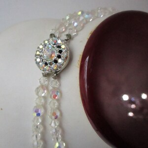 May include: A double strand of clear iridescent crystal beads with a silver clasp featuring a clear rhinestone centre.