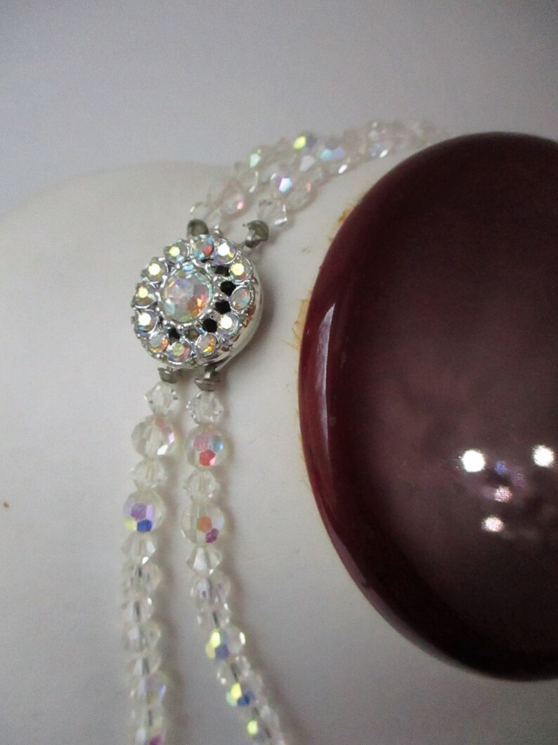 May include: A double strand of clear iridescent crystal beads with a silver clasp featuring a clear rhinestone centre.