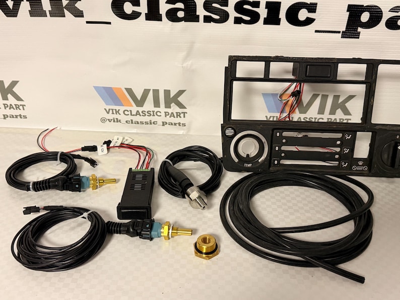 May include: A collection of car components, featuring black wiring, sensors, and a dashboard frame. The parts are displayed on a light surface, with the "VIK Classic Part" logo visible in the background.