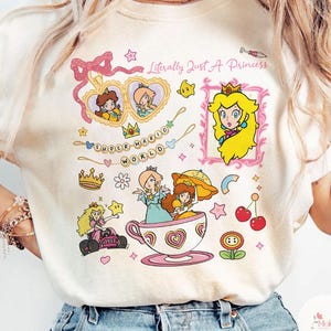 May include: Cream-colored graphic tee featuring various Super Mario World princess illustrations. The design includes Princess Peach, Rosalina, and Daisy, along with the text "Literally Just A Princess" and "Super Mario World".