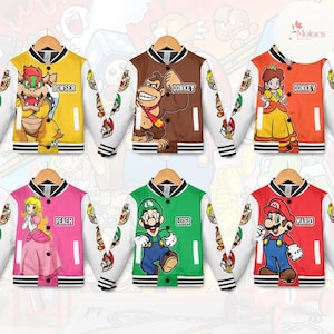 May include: Six colorful varsity jackets featuring characters from the Super Mario video game series. Each jacket has a different character on the front, including Bowser, Donkey Kong, Princess Peach, Luigi, and Mario. The jackets have white sleeves with character-themed designs.