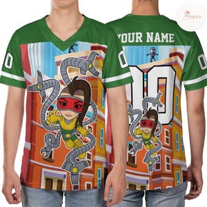 Puede incluir: Camiseta verde y blanca con cuello en V con una ilustraci&oacute;n de dibujos animados de un personaje con brazos mec&aacute;nicos. La parte delantera presenta al personaje sobre un fondo de edificio, y la parte trasera tiene el n&uacute;mero 10 y espacio para un nombre. Las mangas tienen rayas blancas.