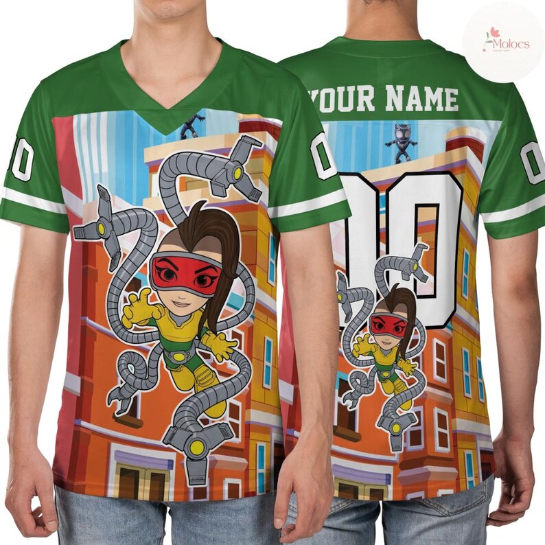 Puede incluir: Camiseta verde y blanca con cuello en V con una ilustraci&oacute;n de dibujos animados de un personaje con brazos mec&aacute;nicos. La parte delantera presenta al personaje sobre un fondo de edificio, y la parte trasera tiene el n&uacute;mero 10 y espacio para un nombre. Las mangas tienen rayas blancas.