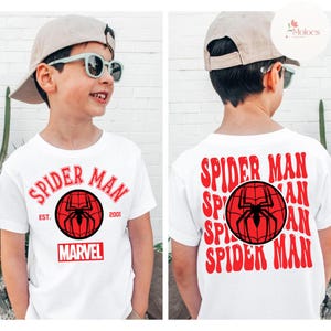 May include: White t-shirt featuring the words "SPIDER MAN" in red, with a red and black spider web graphic. The shirt also has the word "MARVEL" in red. The back of the shirt also has the words "SPIDER MAN" in red.
