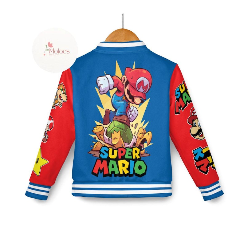 Puede incluir: Una chaqueta de b&eacute;isbol azul y roja con un gr&aacute;fico de Super Mario en la espalda. El gr&aacute;fico presenta a Mario saltando sobre un caparaz&oacute;n de tortuga. La chaqueta tiene rayas blancas en las mangas y en la parte inferior.