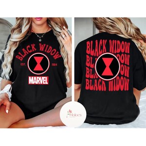 May include: Black t-shirt featuring the text "BLACK WIDOW" in red, with a red and black hourglass symbol. The front of the shirt includes the text "EST. 1984" and the Marvel logo. The back of the shirt repeats the text "BLACK WIDOW".