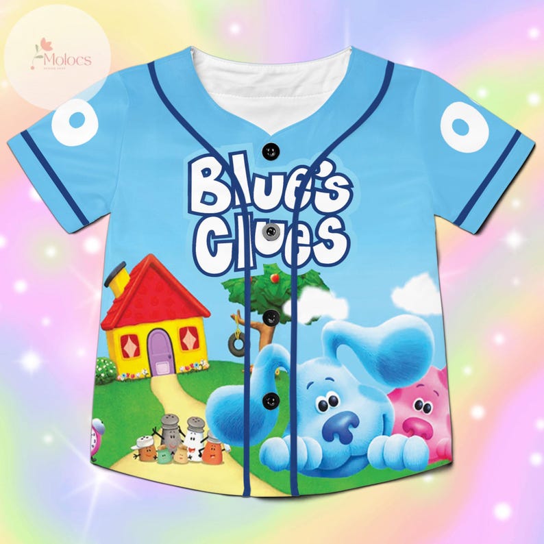 May include: Light blue baseball jersey featuring the phrase "Blue's Clues" in white. The jersey has a cartoon graphic of Blue the dog, a pink pig, a yellow house with a red roof, and a tree. The jersey has a button-up front and blue trim.