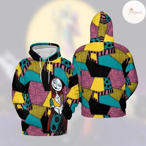Puede incluir: Una sudadera con capucha con un dise&ntilde;o de patchwork colorido en verde azulado, amarillo, rosa y negro. La parte delantera muestra una ilustraci&oacute;n de personaje con pelo largo rojo y una apariencia cosida. La parte trasera de la sudadera con capucha muestra el patr&oacute;n de patchwork.