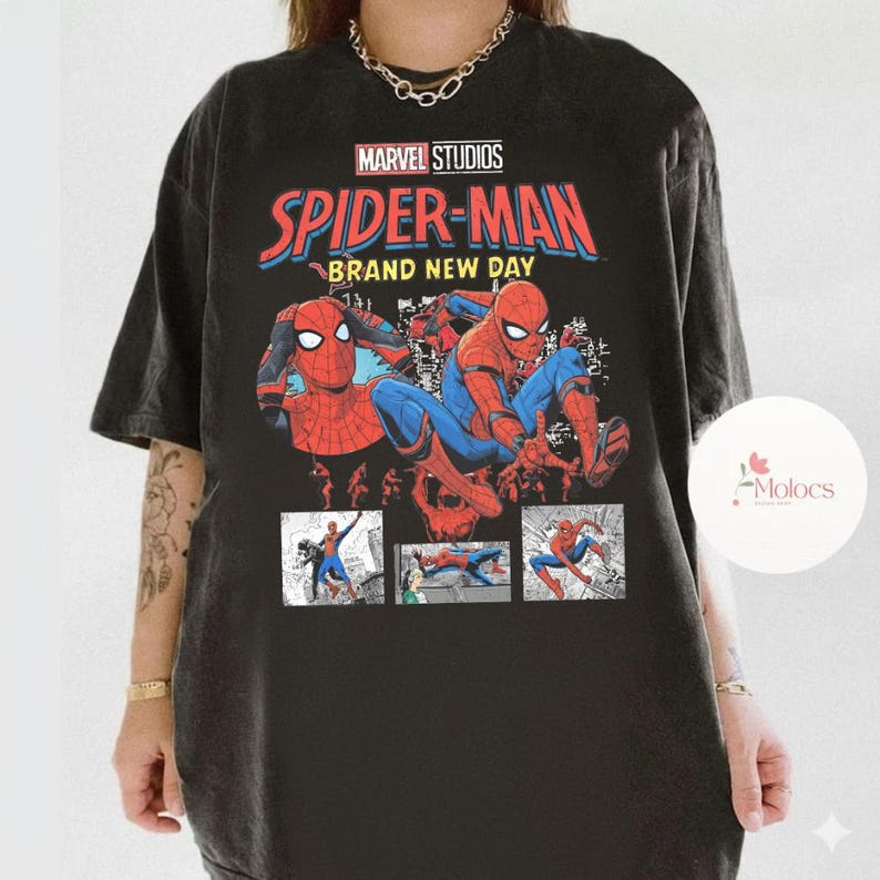 Op de afbeelding: Zwart T-shirt met een Spider-Man-ontwerp van Marvel Studios. Het ontwerp bevat de tekst "Spider-Man Brand New Day" in rood en blauw, samen met stripboekillustraties van Spider-Man in actie.
