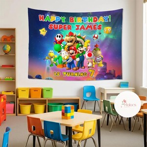 Peut inclure: Une tapisserie color&eacute;e repr&eacute;sentant des personnages de la s&eacute;rie de jeux vid&eacute;o Super Mario. La banni&egrave;re indique "HAPPY BIRTHDAY! SUPER JAMES" et "IS TURNING 7". L'arri&egrave;re-plan est une sc&egrave;ne spatiale vibrante avec des &eacute;toiles et des plan&egrave;tes.