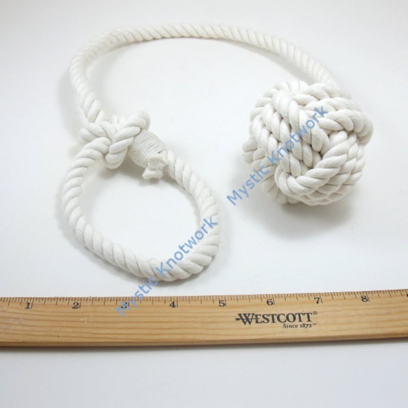 May include: White cotton rope tied into a large knot, with a smaller loop knot at the other end. The rope is about 8 inches long.