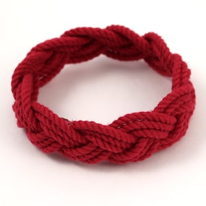May include: A red rope bracelet with a braided design.