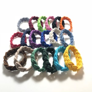 May include: A collection of 18 colorful braided rope bracelets in various colors, including red, blue, green, yellow, and purple.