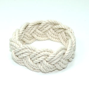 May include: A white rope bracelet with a braided design.