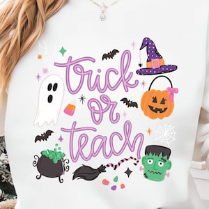 May include: A white long-sleeve sweatshirt featuring a graphic print with the purple text "trick or teach" surrounded by Halloween icons including a white ghost, a purple witch hat, an orange pumpkin bucket, a black cauldron, and a green monster.