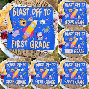 May include: A blue square sign featuring the text BLAST OFF TO FIRST GRADE in yellow letters. The design includes a yellow rocket, a box of crayons, a notebook, and colorful stars. A yellow pencil-shaped ribbon is attached to the top left corner.