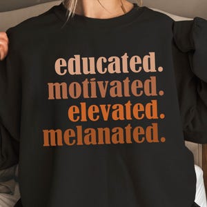 Könnte beinhalten: Schwarzes Sweatshirt mit den Worten "educated. motivated. elevated. melanated." in einem Farbverlauf aus Braun und Orange. Das Sweatshirt hat einen Rundhalsausschnitt.