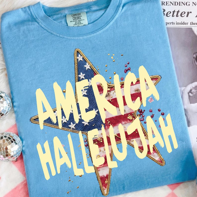 Pu&ograve; includere: T-shirt Comfort Colors azzurra con un design a stella con il motivo della bandiera americana e le parole "AMERICA HALLELUJAH" in giallo. La stella &egrave; bordata d'oro, con macchie dorate. La maglietta ha un girocollo.