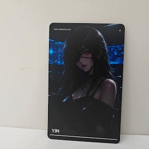 May include: A rectangular metal sign featuring a dark-haired character with a red eye and an eyepatch, wearing a black top. The background displays a blue digital interface. The text UWU UNDERGROUND is at the top and YIN is at the bottom.