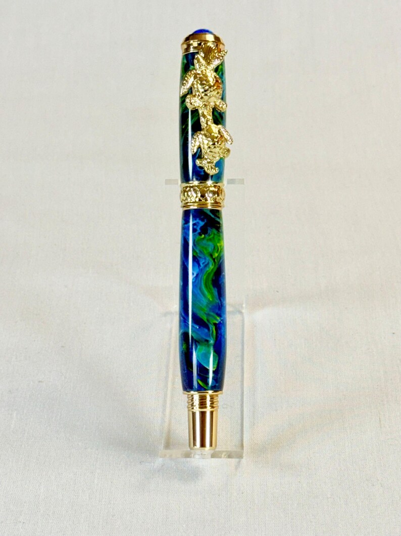 The Sea Turtle Roller Ball pen features a stunning blue-ocean synthetic Fire Opal, turtle shell texture, and sea turtle clip. Truly a turtle lover gift. It comes either as a Rollerball or Fountain Pen. The cap posts securely with wide threads that won't cross. Hawaiian Honu Pen that has beautiful ocean themed features. One of my favorite Sea Creatures is the Sea Turtle. This Pen has it all. The pen comes with a windowed pen box making this item gift-ready.