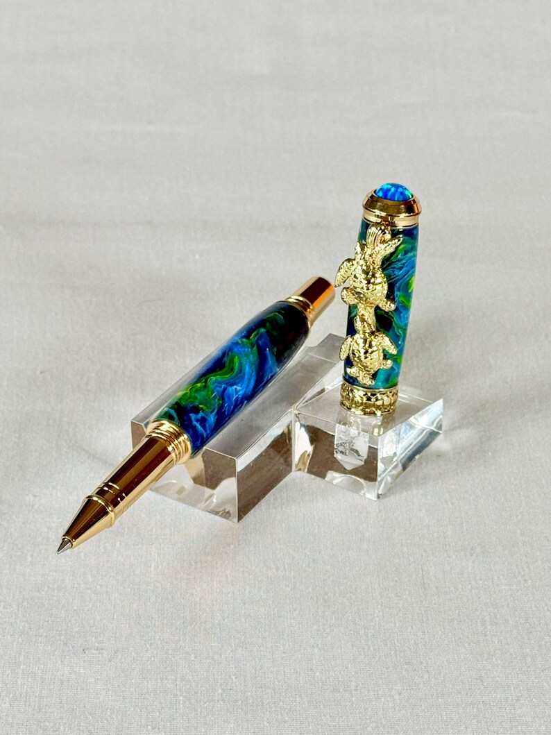 The Sea Turtle Roller Ball pen features a stunning blue-ocean synthetic Fire Opal, turtle shell texture, and sea turtle clip. Truly a turtle lover gift. It comes either as a Rollerball or Fountain Pen. The cap posts securely with wide threads that won't cross. Hawaiian Honu Pen that has beautiful ocean themed features. One of my favorite Sea Creatures is the Sea Turtle. This Pen has it all. The pen comes with a windowed pen box making this item gift-ready.