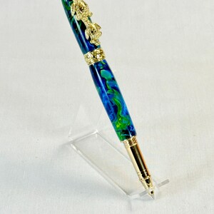 The Sea Turtle Roller Ball pen features a stunning blue-ocean synthetic Fire Opal, turtle shell texture, and sea turtle clip. Truly a turtle lover gift. It comes either as a Rollerball or Fountain Pen. The cap posts securely with wide threads that won't cross. Hawaiian Honu Pen that has beautiful ocean themed features. One of my favorite Sea Creatures is the Sea Turtle. This Pen has it all. The pen comes with a windowed pen box making this item gift-ready.