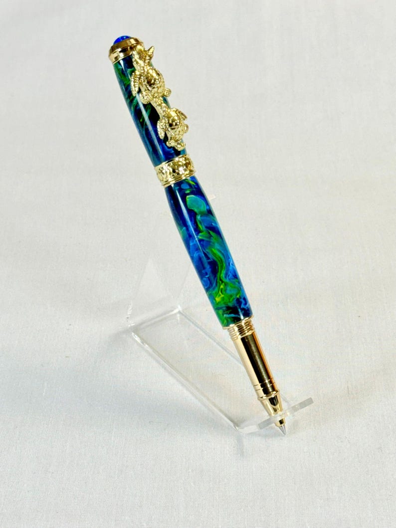 The Sea Turtle Roller Ball pen features a stunning blue-ocean synthetic Fire Opal, turtle shell texture, and sea turtle clip. Truly a turtle lover gift. It comes either as a Rollerball or Fountain Pen. The cap posts securely with wide threads that won't cross. Hawaiian Honu Pen that has beautiful ocean themed features. One of my favorite Sea Creatures is the Sea Turtle. This Pen has it all. The pen comes with a windowed pen box making this item gift-ready.