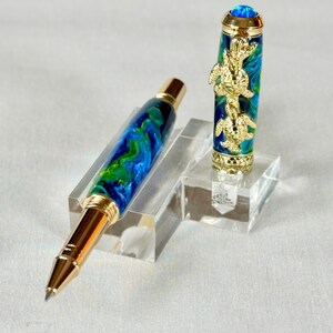 The Sea Turtle Roller Ball pen features a stunning blue-ocean synthetic Fire Opal, turtle shell texture, and sea turtle clip. Truly a turtle lover gift. It comes either as a Rollerball or Fountain Pen. The cap posts securely with wide threads that won't cross. Hawaiian Honu Pen that has beautiful ocean themed features. One of my favorite Sea Creatures is the Sea Turtle. This Pen has it all. The pen comes with a windowed pen box making this item gift-ready.