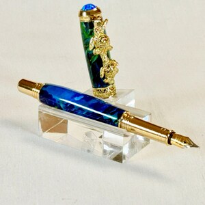 The Sea Turtle Roller Ball pen features a stunning blue-ocean synthetic Fire Opal, turtle shell texture, and sea turtle clip. Truly a turtle lover gift. It comes either as a Rollerball or Fountain Pen. The cap posts securely with wide threads that won't cross. Hawaiian Honu Pen that has beautiful ocean themed features. One of my favorite Sea Creatures is the Sea Turtle. This Pen has it all. The pen comes with a windowed pen box making this item gift-ready.